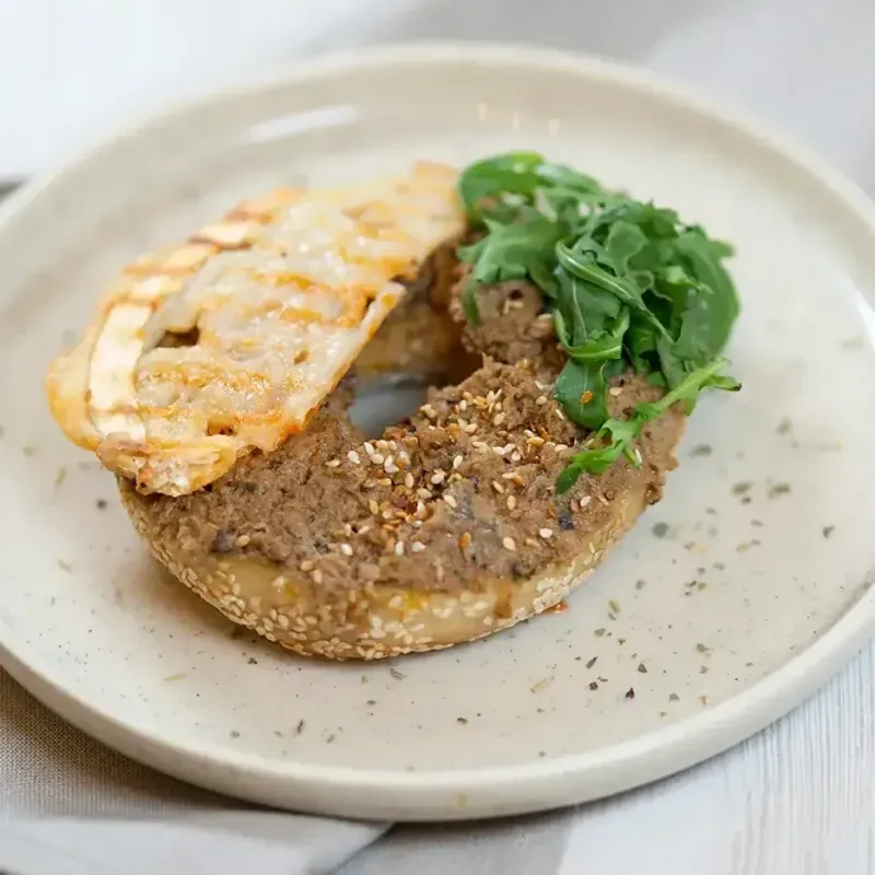 halber Bagels mit würzigem Hummus und getrockneter Tomate.